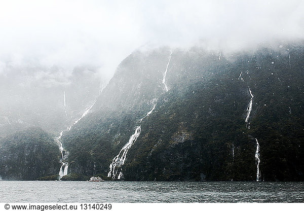 Scenic view of waterfalls at Milford sound during foggy weather
