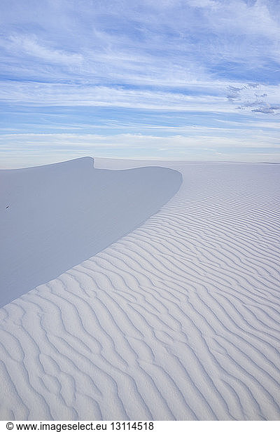 Scenic view of wave patterns on desert against cloudy sky at White Sands National Monument