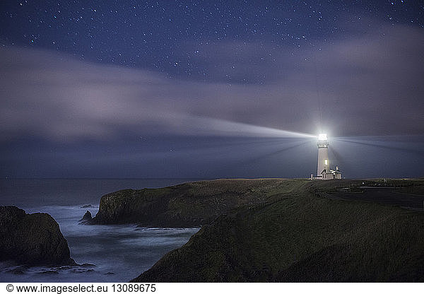 Scenic view of Yaquina Head Lighthouse on shore against star field