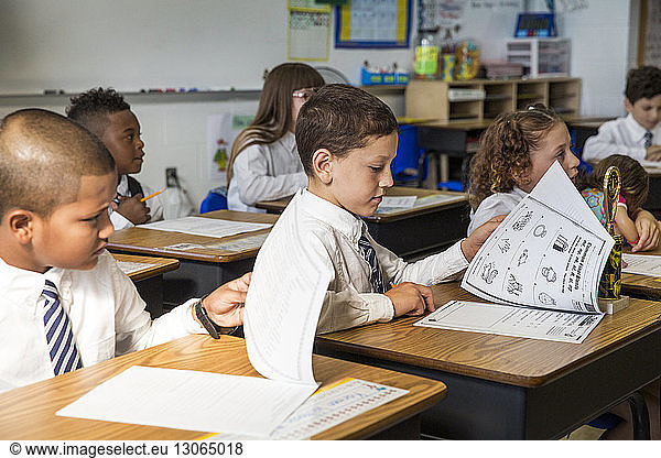 Schüler  die während des Unterrichts im Klassenzimmer Bücher anschauen