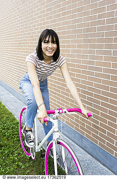 Schöne Frau beim Radfahren an der Wand