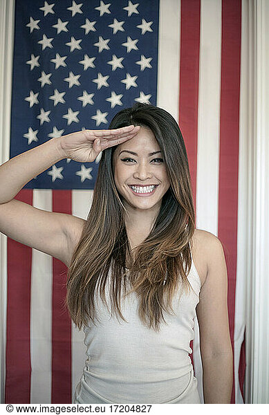 Schöne Frau salutiert vor der amerikanischen Flagge