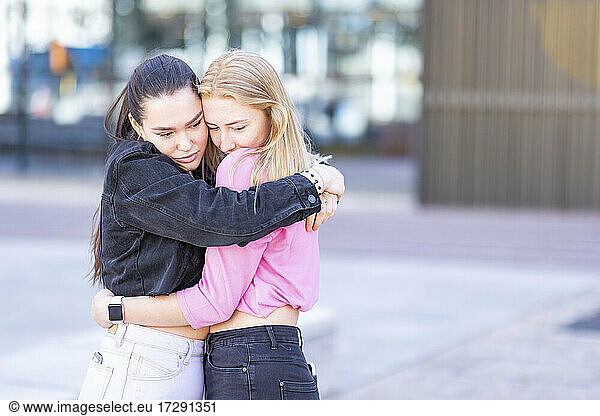 Schöne Freundinnen umarmen sich in der Stadt