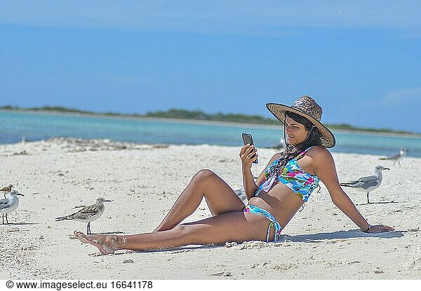 Schöne junge Frau  die am Strand mit dem Handy telefoniert.