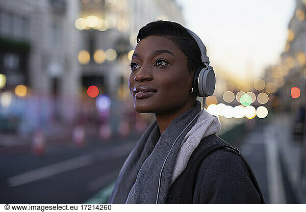 Schöne junge Frau in Kopfhörer auf der Straße der Stadt