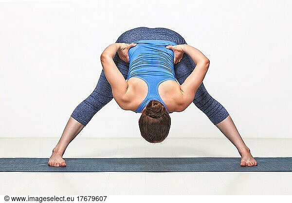 Schöne sportliche fitte Frau übt Ashtanga Vinyasa Yoga Asana Prasarita padottanasana B  breitbeinige Vorwärtsbeuge B
