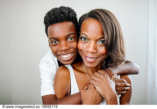 Schöner glücklicher schwarzer Junge  der seine schöne Mutter von hinten umarmt