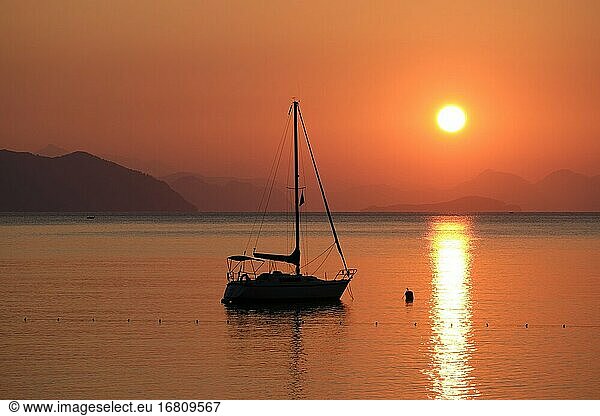 Schöner Sonnenaufgang in der Ägäis mit Boot und Bergen  Strand von Turunc  Türkei.