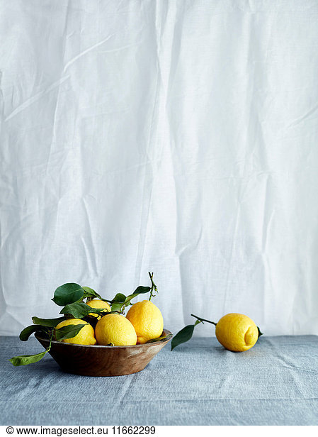 Schale mit frischen Zitronen in Schale auf Tischdecke