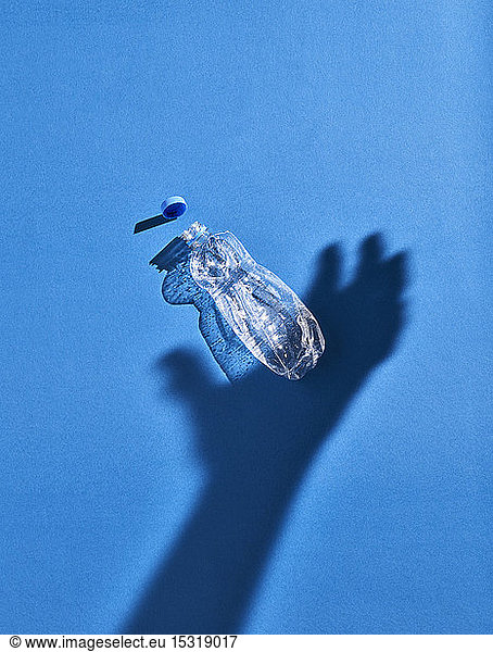 Schatten einer Hand und einer Plastikflasche  blauer Hintergrund