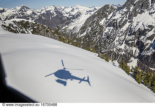 Schatten eines Hubschraubers auf einer verschneiten Berglandschaft