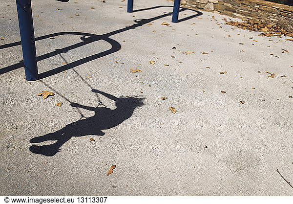 Schatten eines im Park schwingenden Jungen