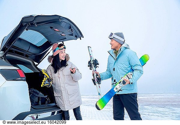 Schieben Sie die jungen Paare die Propeller-Köpfe  um die Skier auf den Kofferraum zu setzen