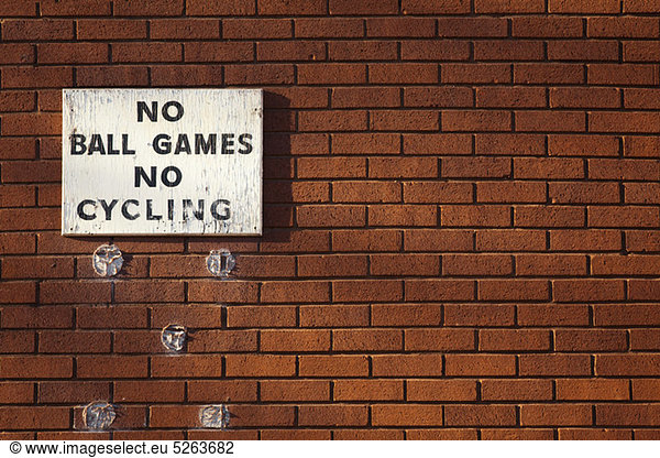 Schild an der Ziegelwand  auf dem steht: Keine Ballspiele  kein Radfahren.
