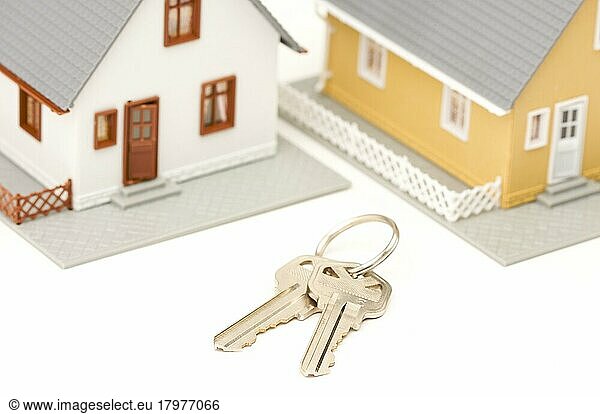 Schlüssel und Häuser vor einem weißen Hintergrund. Der Fokus liegt auf den Schlüsseln