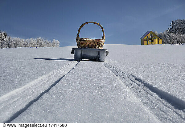 Schlitten  der einen Korb über eine hügelige  verschneite Winterlandschaft transportiert  Estland