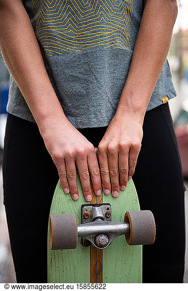 Schlittschuhläuferin posiert mit ihrem Skateboard