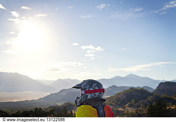 Schmutziger Radfahrer  der am sonnigen Tag Berge gegen den Himmel schaut