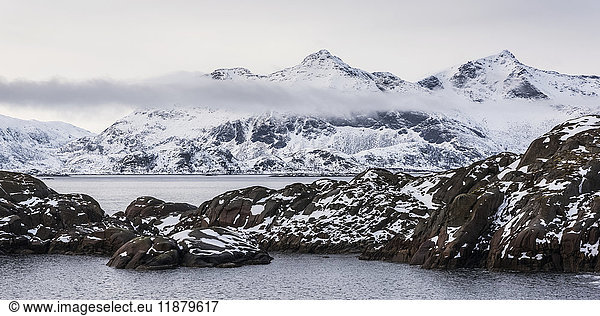 Schneelandschaft mit zerklüfteten Bergen und Meereswasser; Nordland  Norwegen'.
