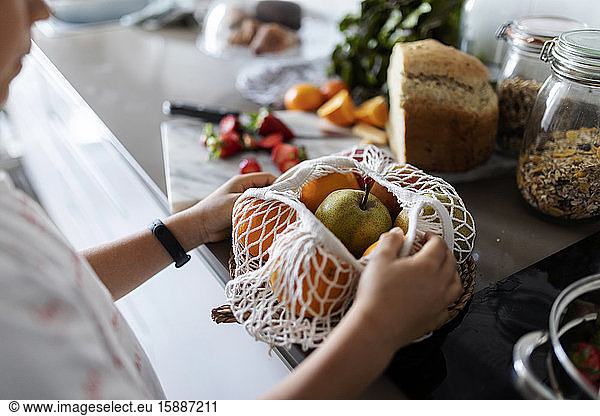 Schnittansicht eines Jungen beim Auspacken von Früchten auf der Küchentheke