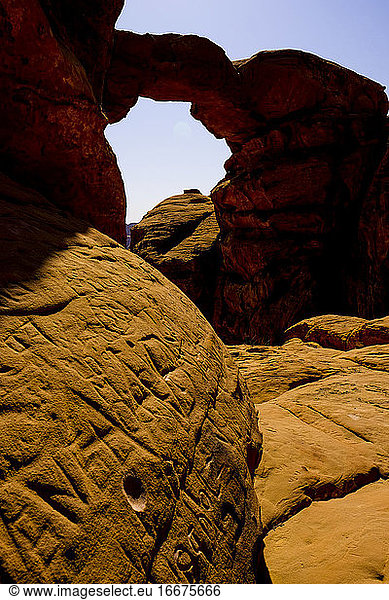 Schnitzereien in einer Felswand unter einem Felsbogen in Wadi Rum  Jordanien