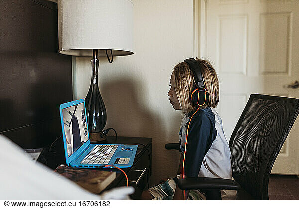 School age boy distance learning in hotel room during pandemic