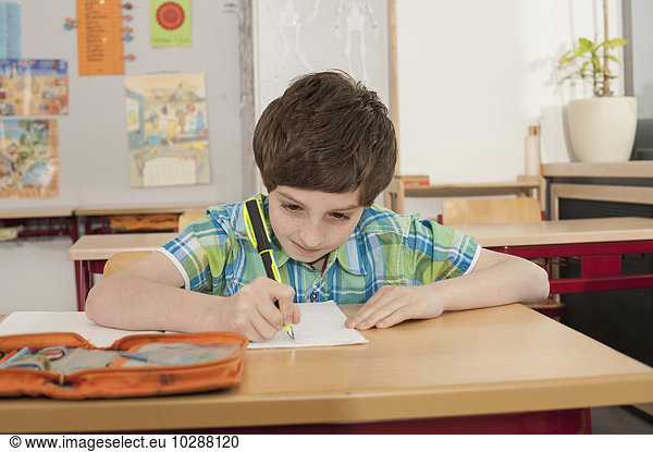Schoolboy writing in a notebook  Munich  Bavaria  Germany