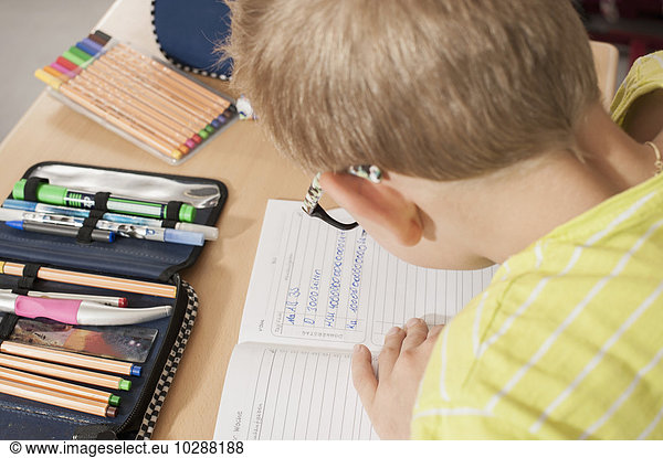 Schoolboy writing in notebook  Munich  Bavaria  Germany