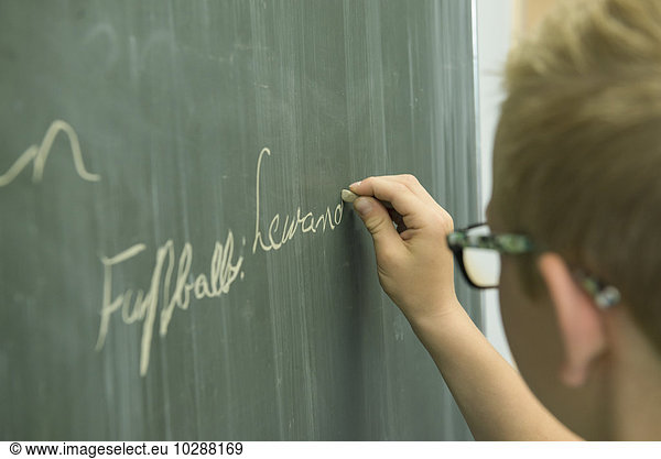Schoolboy writing on blackboard in classroom  Munich  Bavaria  Germany