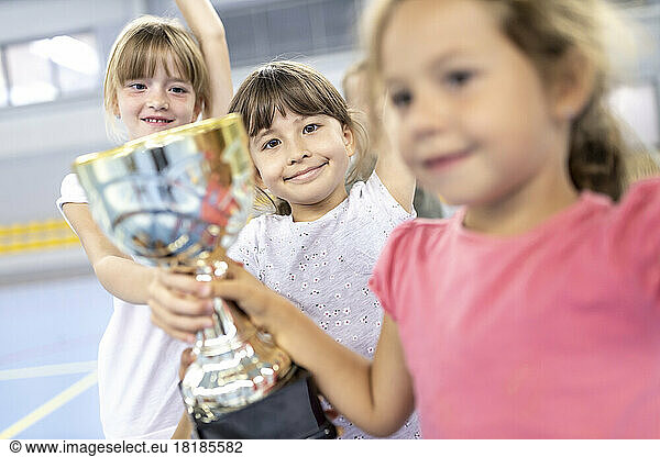 Schoolgirls celebrating victory with trophy at school sports court