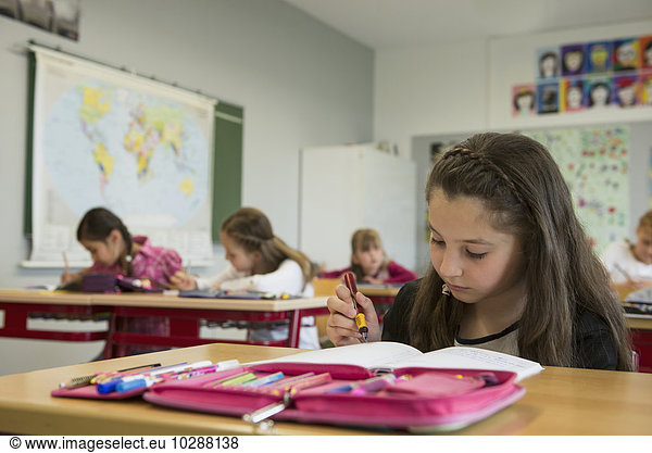 Schoolgirls writing notebooks in classroom  Munich  Bavaria  Germany