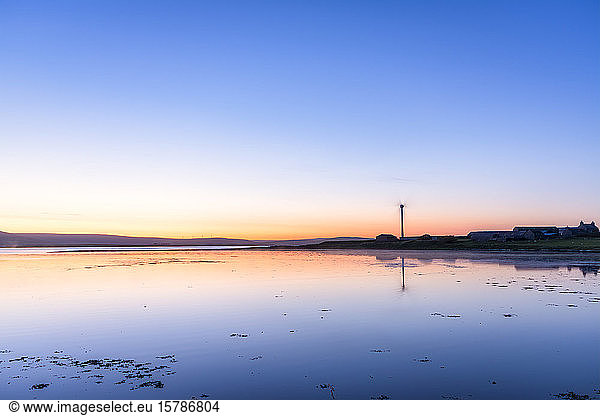 Schottland  Orkney-Inseln  Rennibister  Windturbine  die bei Sonnenuntergang im Wasser reflektiert wird