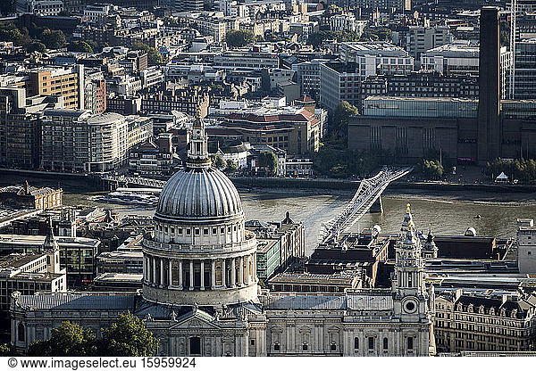 Schrägansicht auf die von Christopher Wren entworfene Kuppel der St. Paul's Cathedral sowie auf die Millennium Bridge und die Tate Modern über die Themse in London