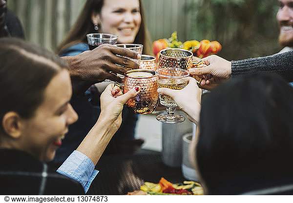 Schrägansicht auf glückliche Freunde  die im Hinterhof sitzen und auf Getränke anstoßen