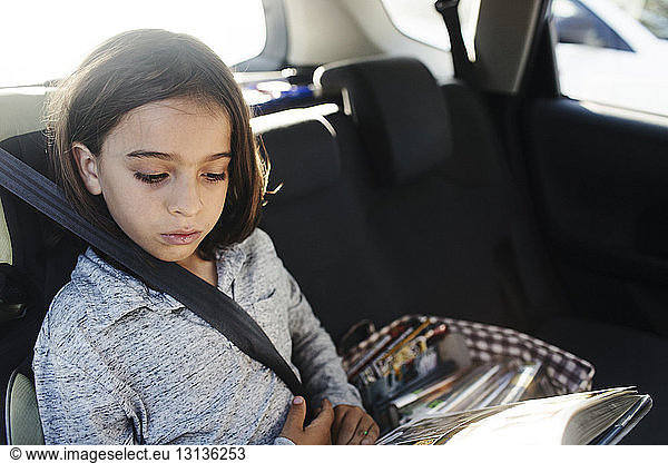 Schrägansicht eines ernsthaften Jungen  der im Auto sitzt und ein Buch liest