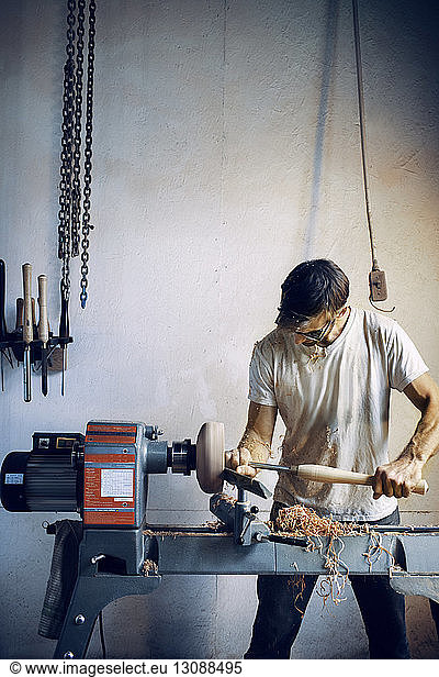 Schreiner hält Meißel beim Formen einer Holzschüssel in der Werkstatt
