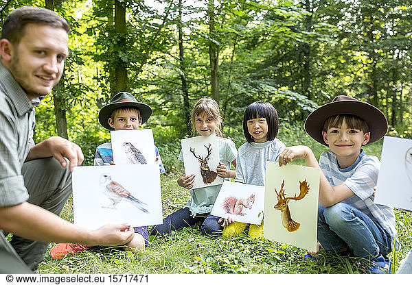 Schulkinder machen Naturstudien  halten Bilder von Tieren