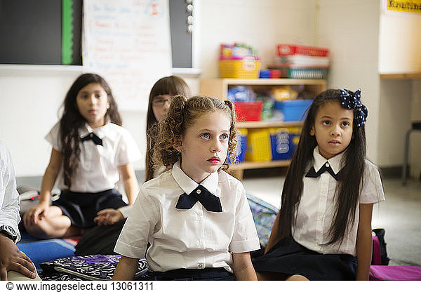 Schulmädchen sitzen im Klassenzimmer auf dem Boden