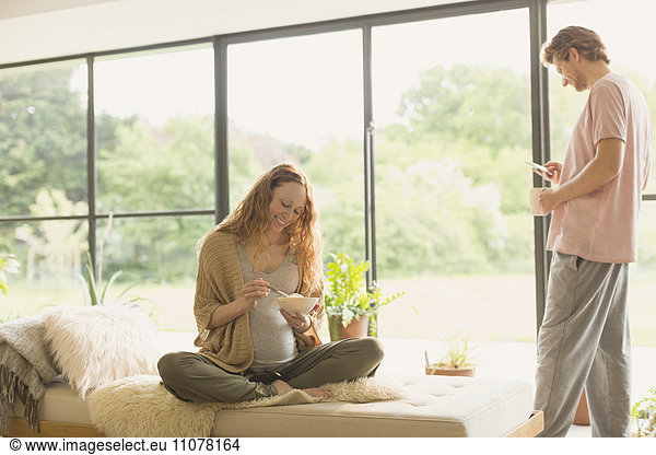 Schwangere Paare essen und trinken Kaffee im Wohnzimmer