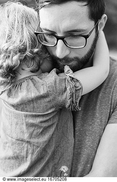 Schwarz-Weiß-Nahaufnahme eines Millennial-Vaters  der seine Tochter tröstet