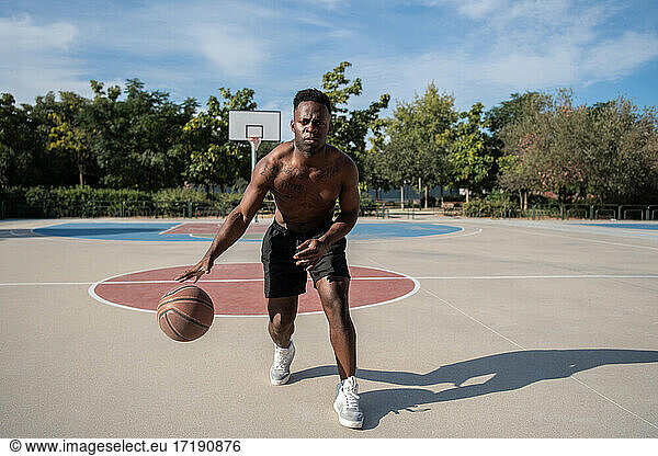 Schwarzer Basketballspieler ohne Hemd dribbelt Ball