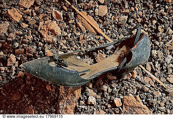 Schwarzer Damenschuh mit Absatz und Schleife am Boden  Maroder Schuh aus Leder  verrotteter Schuh  Schuhwrack  vergammelter Treter  ausgelatschter Schuh  abgetragener Schuh  alter Schuh
