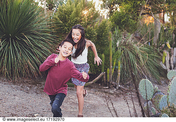 Schwester und Bruder laufen in einem Kaktusgarten.