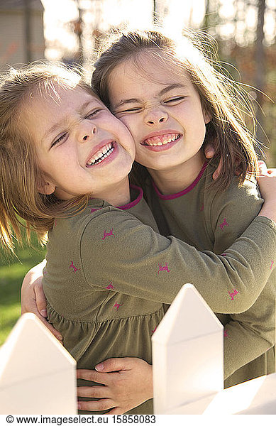 Schwestern umarmen sich lächelnd in der Sonne