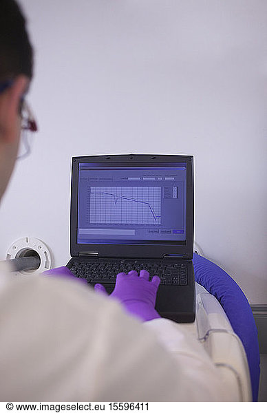 Scientist examining a medical report on a laptop