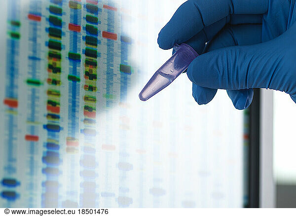 Scientist holding a vial containing a DNA sample ready for testing.