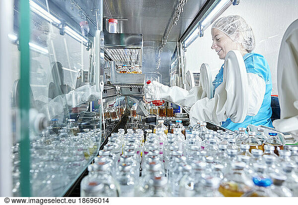 Scientist holding chemical bottle inside microbiological safety cabinet