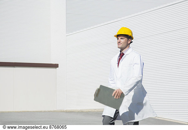 Scientist in hard-hat with clipboard walking outdoors