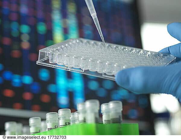 Scientist injecting sample in microtiter plate at laboratory