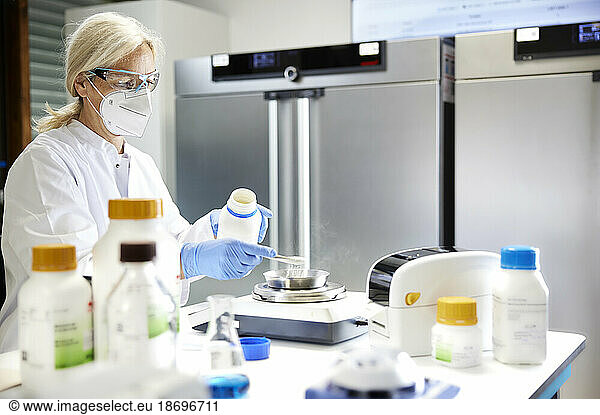 Scientist measuring chemical on weighing scale in laboratory